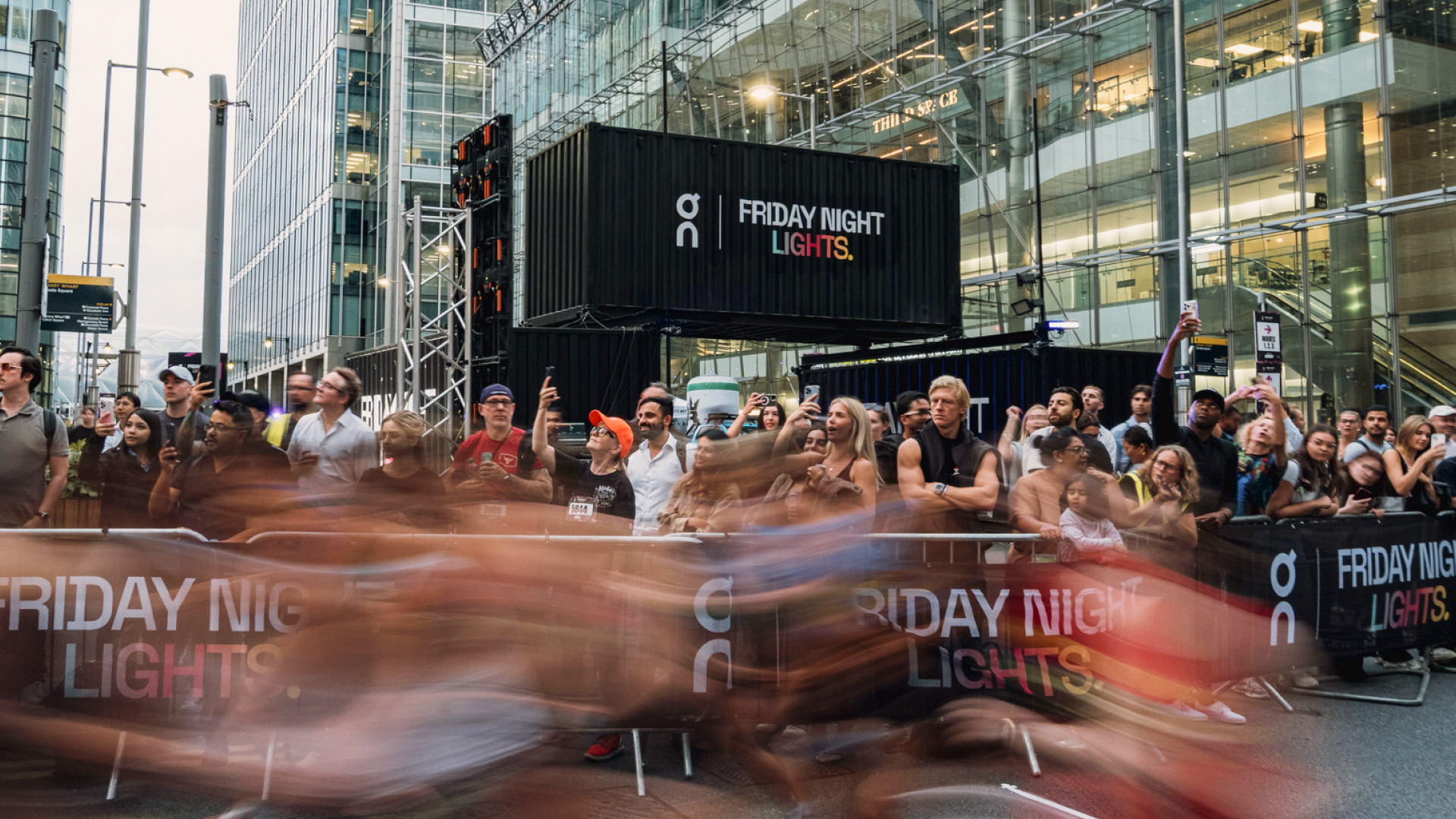 Runners passing the On Running Friday Night Lights event village in Canary Wharf