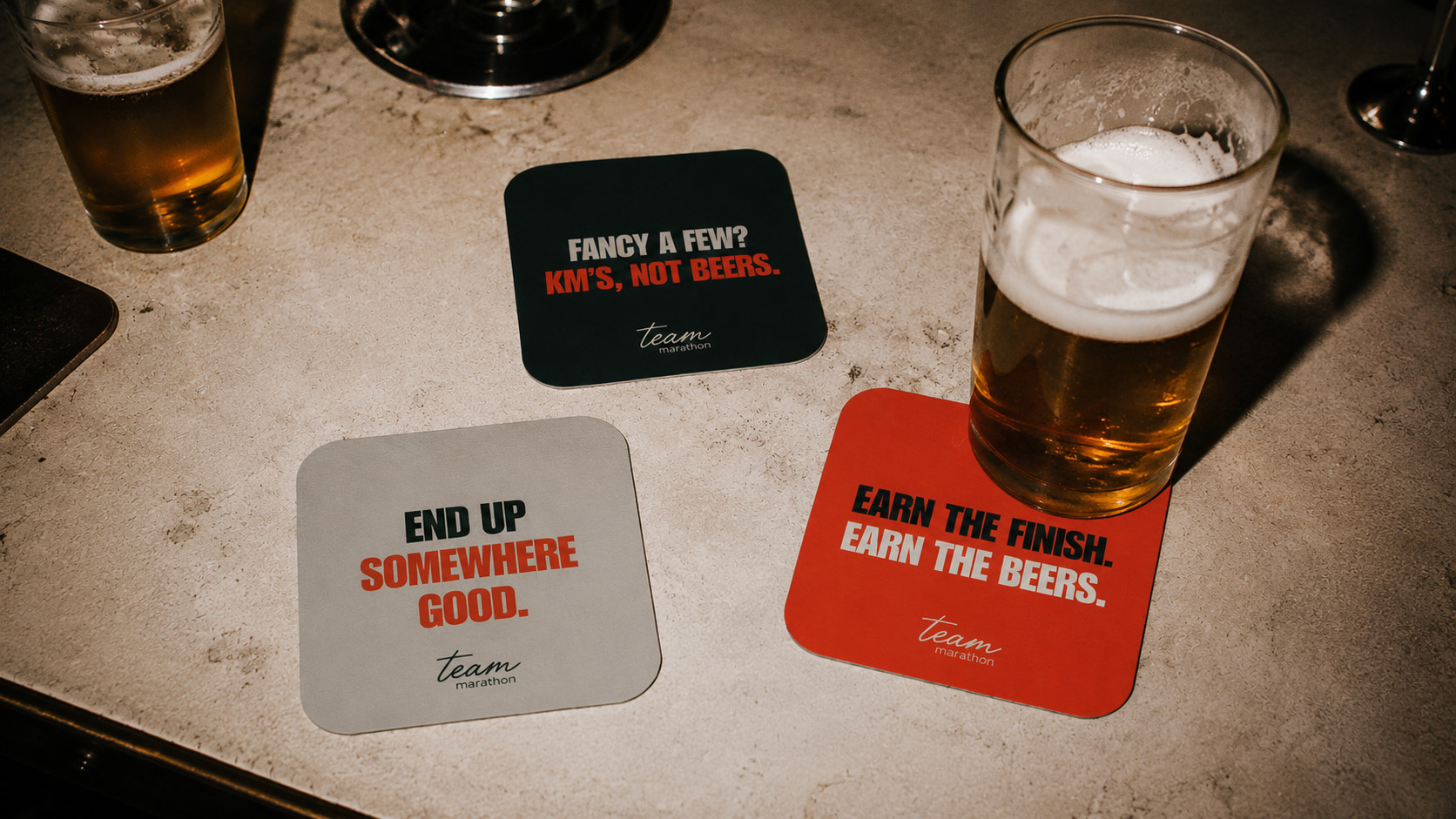 Team Marathon branded coasters featuring the event tone of voice